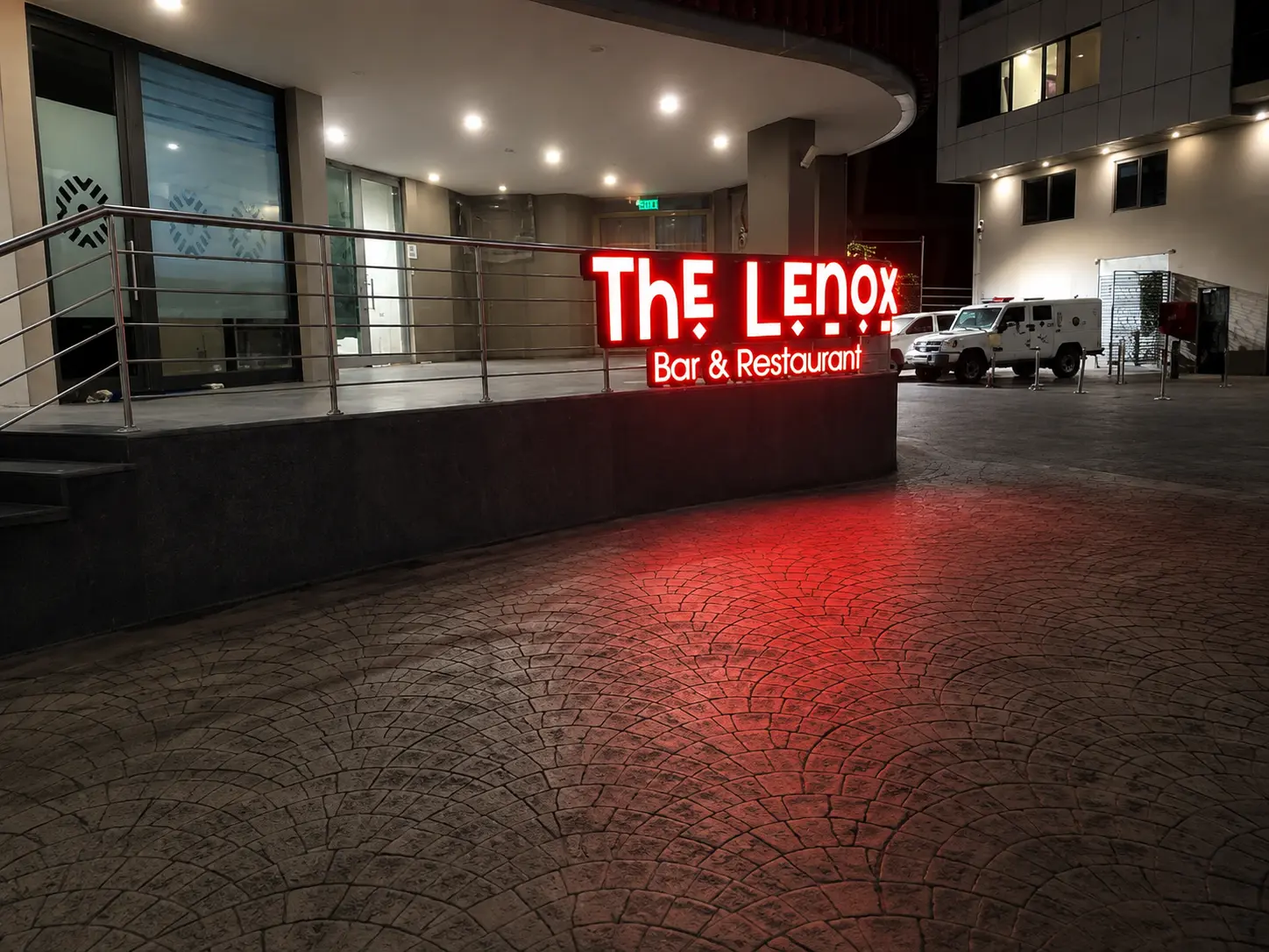 Glowing red neon sign for The Lenox Bar & Restaurant on a patio